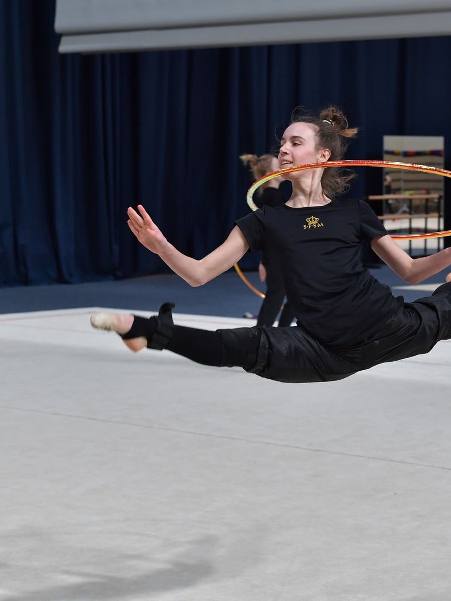 Mariia Miroshnik mid-leap with a hoop during a rhythmic gymnastics practice