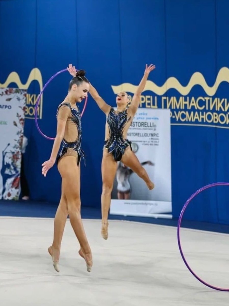 Mariia Miroshnik and a teammate jumping with hoops at a competition